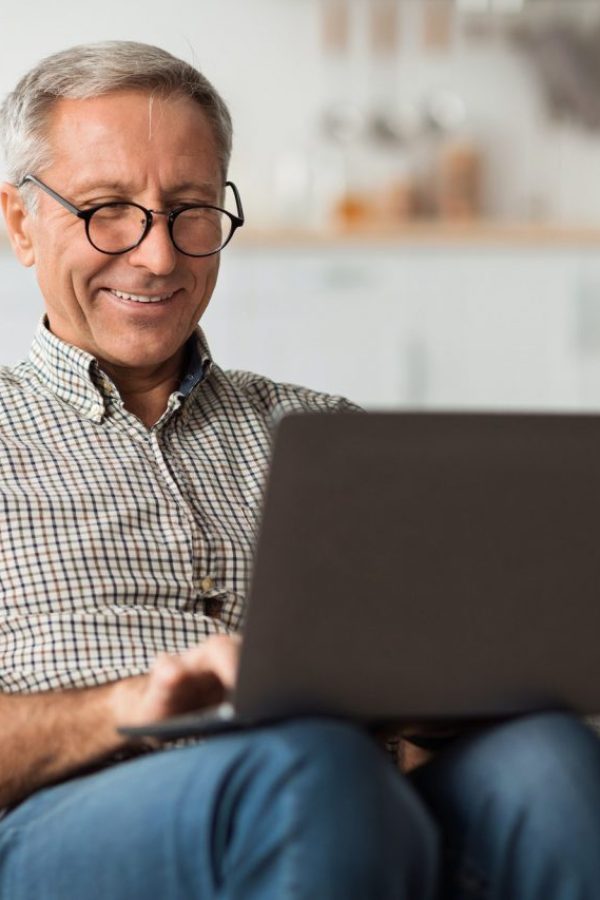 happy-senior-man-using-laptop-browsing-internet-sitting-at-home.jpg